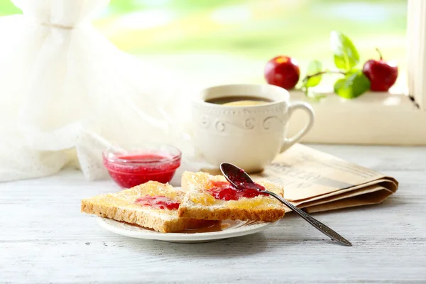 Toasts with jam on plate and cup of tea on bright background — Stock Photo, Image