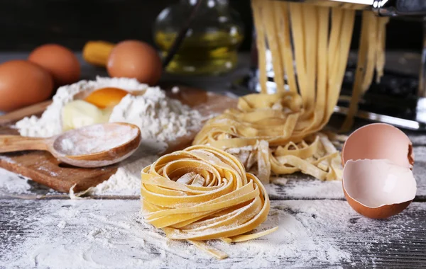 Metal pasta maker machine and ingredients for pasta on wooden background — Stock Photo, Image