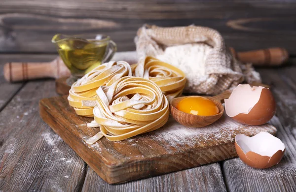Syrové domácí těstoviny a ingredience pro těstoviny na dřevěné pozadí — Stock fotografie