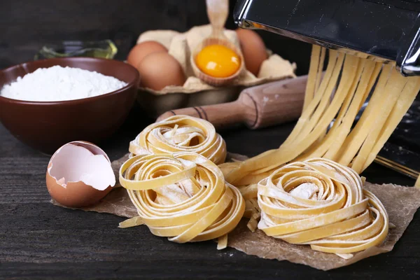 Máquina de hacer pasta de metal e ingredientes para pasta sobre fondo de madera —  Fotos de Stock