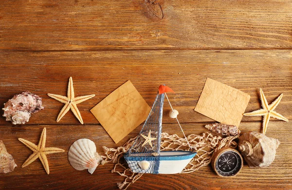 Красивая морская композиция с лодкой и раковинами на деревянном фоне — стоковое фото