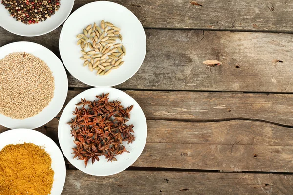 Different spices on plates, on old wooden table — Stock Photo, Image