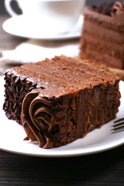 Smaczny sztuk ciasto czekoladowe na drewnianym stole tło — Zdjęcie stockowe