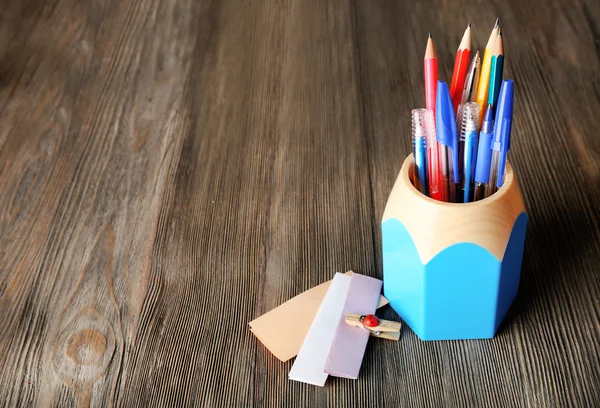 Colorful pens and pencils in cup on wooden table background — Stock Photo, Image