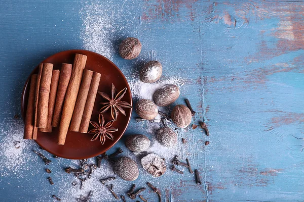 Palitos de canela, anís estrellado, nuez moscada y clavo de olor sobre fondo de mesa de madera de color —  Fotos de Stock