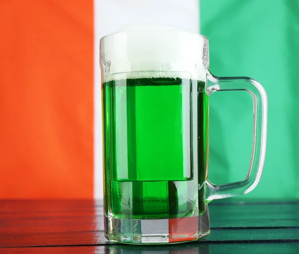 Glass of green beer on Ireland flag background — Stock Photo, Image