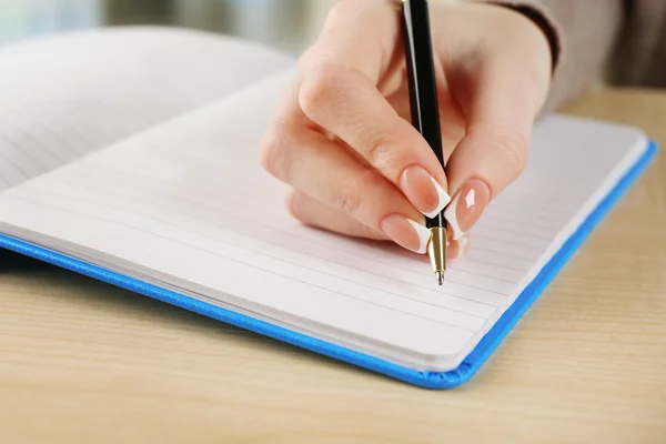 Weibliche Hand mit Schreibstift auf Notizbuch, Nahaufnahme — Stockfoto