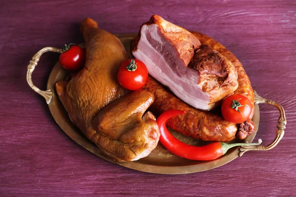 Assortment of smoked meat on metal tray on color wooden table background — Stock Photo, Image