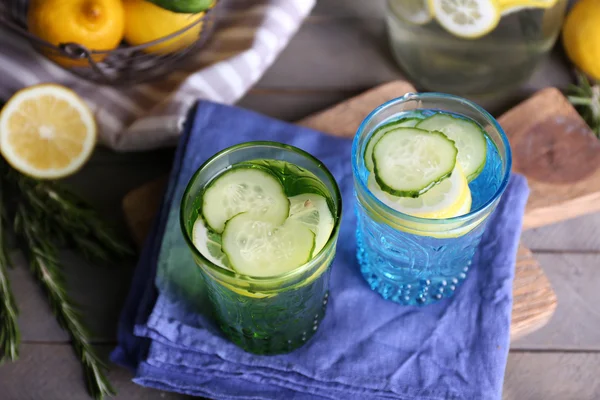 Fresh water with lemon and cucumber in glassware with napkin on wooden table, closeup — Stock Photo, Image