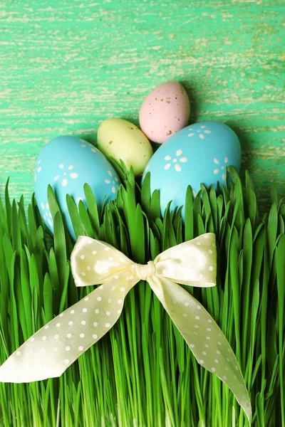 Easter eggs and grass on wooden background — Stock Photo, Image