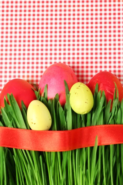 Ovos de Páscoa e grama no fundo de papel colorido — Fotografia de Stock