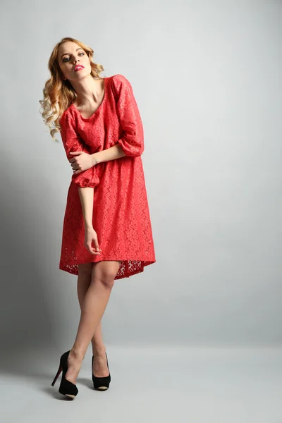 Gyönyörű fiatal nő, színes ruhában pózol a világos háttér — Stock Fotó