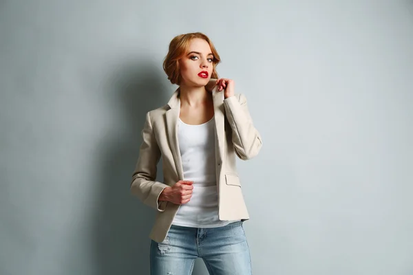 Hermosa joven con chaqueta y jeans posando sobre fondo claro — Foto de Stock