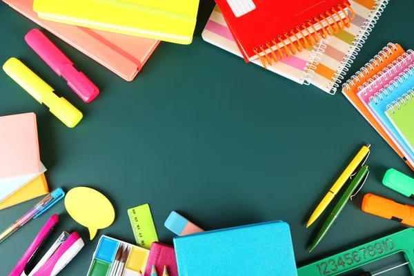 Bright school supplies on blackboard background — Stock Photo, Image