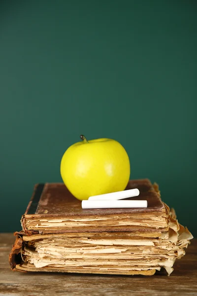 Libros antiguos, manzana y tiza sobre fondo de pizarra —  Fotos de Stock