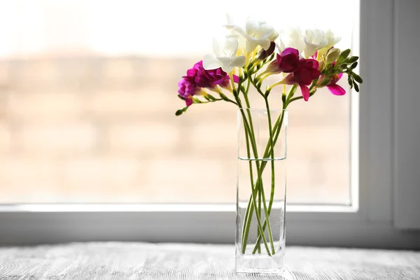 Prachtige Lentebloemen in glazen vaas op vensterbank achtergrond — Stockfoto