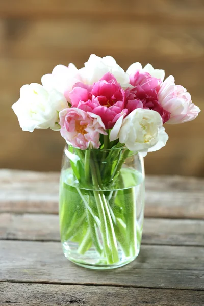 Bellissimi tulipani in vaso di vetro su fondo di legno — Foto Stock