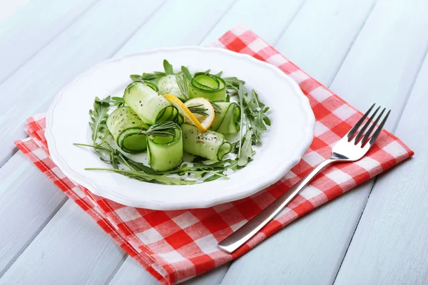 Talíř zelený salát, okurka, rukola a rozmarýnem na dřevěné pozadí — Stock fotografie