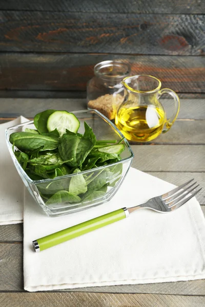 Ciotola di vetro di insalata verde con cetriolo e spinaci su sfondo di legno — Foto Stock