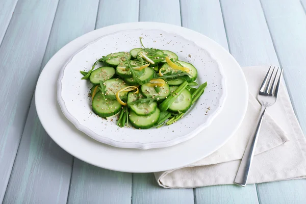 Ahşap zemin üzerine salatalık, roka ve limon kabuğu ile yeşil salata — Stok fotoğraf