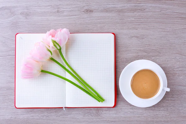 Beautiful tulips with diary and cup of coffee on wooden table, top view — Stock Photo, Image