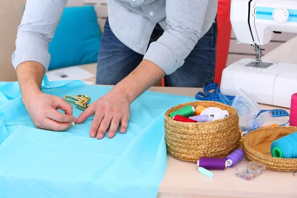 Male dressmaker cut fabric on table — Stock Photo, Image