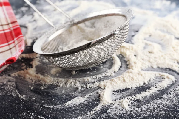 Peneirando farinha através da peneira na mesa de madeira, close-up — Fotografia de Stock