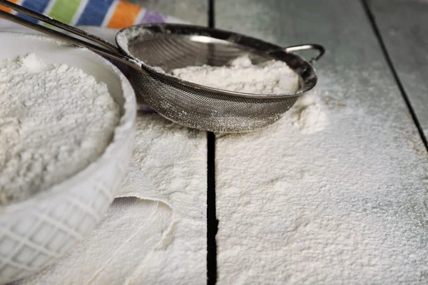 Sifting flour through sieve on wooden table, closeup — Stock Photo, Image