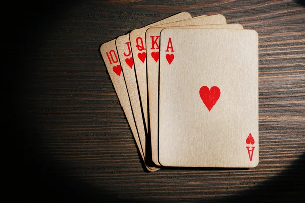 Playing cards in light on wooden table, top view — Stock Photo, Image