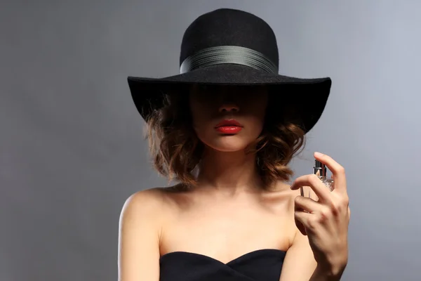 Hermosa mujer con frasco de perfume sobre fondo gris —  Fotos de Stock