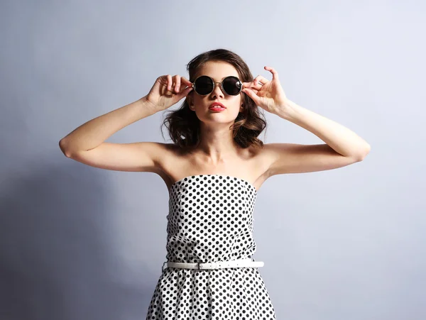Porträt des schönen Modells im Punktekleid mit Sonnenbrille auf grauem Hintergrund — Stockfoto