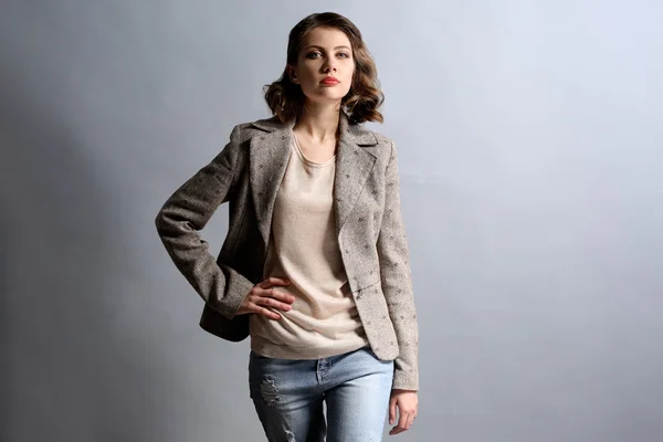 Portrait of beautiful model in jeans and jacket on gray background — Stock Photo, Image