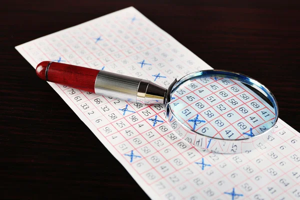 Analisando bilhete de loteria com lupa, close-up — Fotografia de Stock