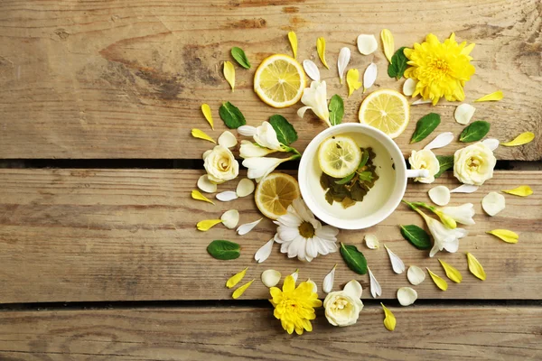 Tazza di tisana con bellissimi fiori, su sfondo di legno — Foto Stock