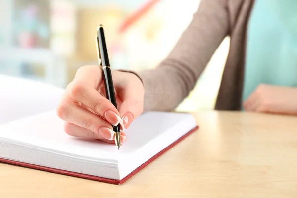 Vrouwelijke hand met pen schrijven op notebook, close-up Rechtenvrije Stockafbeeldingen