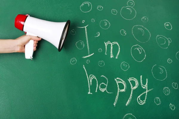 Hand holding megaphone on blackboard background — Stock Photo, Image