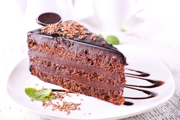 Delicioso bolo de chocolate na placa na mesa no fundo claro — Fotografia de Stock