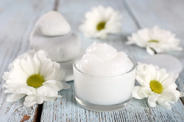 Cosmetische crème met bloemen en spa stenen op houten achtergrond — Stockfoto