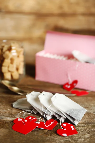 Heart shaped teabag tags and Cup of tea with on wooden background — Stock Photo, Image