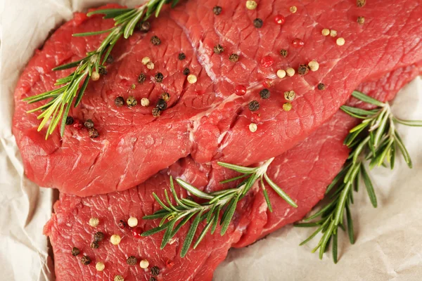 Filete de ternera crudo con romero y especias en papel de cerca — Foto de Stock