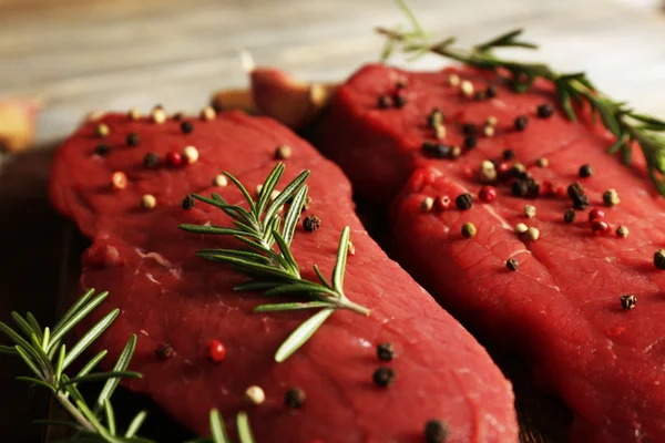 Syrové hovězí steak s rozmarýnem a koření na prkénko na dřevěné pozadí — Stock fotografie