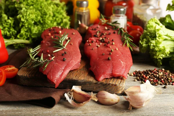 Raw beef steak with spices and greens on table close up — Stock Photo, Image