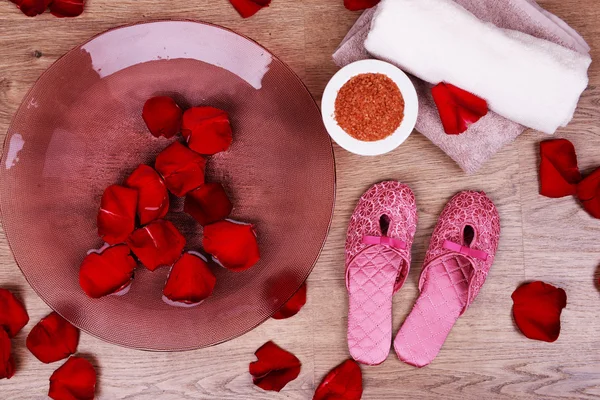 Cuenco spa con agua, pétalos de rosa, toalla y zapatillas sobre fondo claro. Concepto de pedicura o tratamiento de spa natural — Foto de Stock