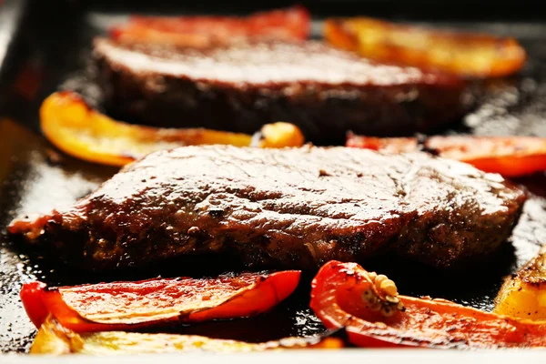 Composition with tasty roasted meat and sliced pepper on pan, tomatoes and rosemary sprigs on wooden background — Stock Photo, Image