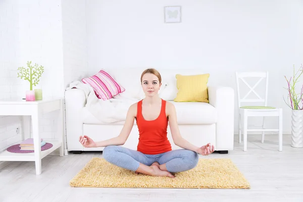 Jovem fazendo ioga em casa — Fotografia de Stock
