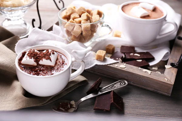Cioccolata calda con marshmallow in tazza, su vassoio, su sfondo di legno a colori — Foto Stock