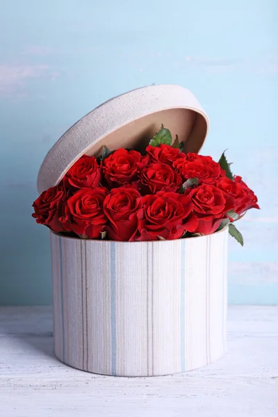 Buquê de rosas vermelhas em caixa têxtil sobre fundo de madeira — Fotografia de Stock