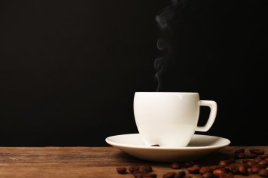 Siyah arka plan üzerine ahşap masa üzerinde uçan daire ile sıcak kahve