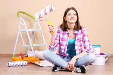 Güzel kız boyama duvar için ekipman ile katta oturan