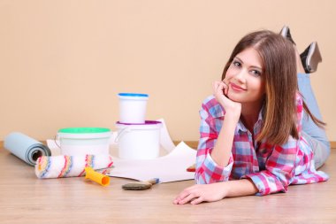 Güzel kız boyama duvar için ekipman ile yerde yatarken